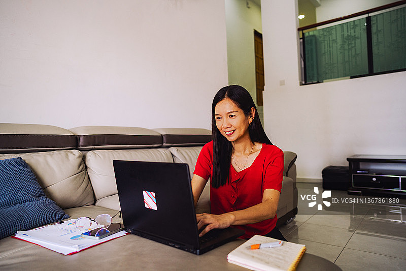亚洲女学生在家学习并记录教授的笔记图片素材