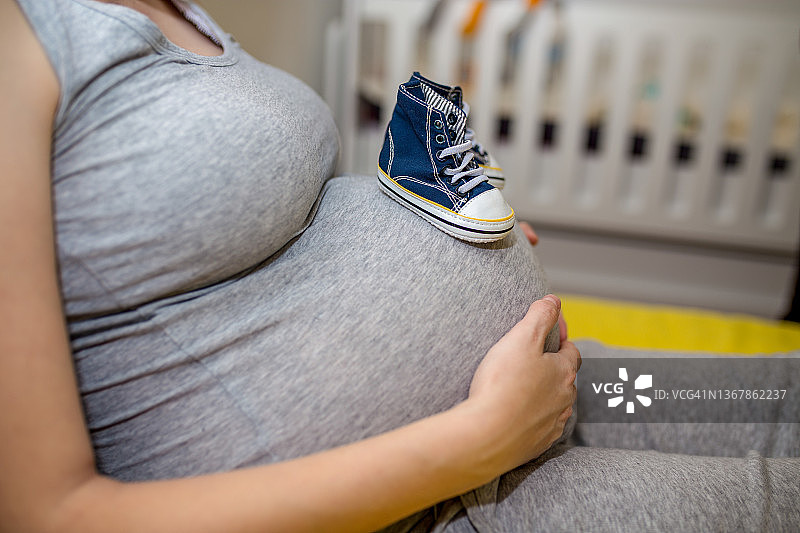 孕妇手拿小鞋靠近腹部图片素材