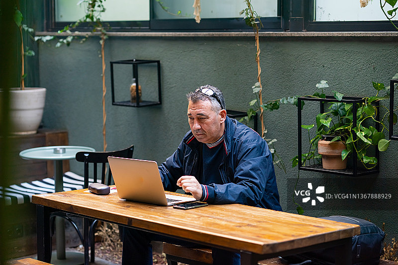 成年男子在咖啡馆用笔记本电脑工作图片素材