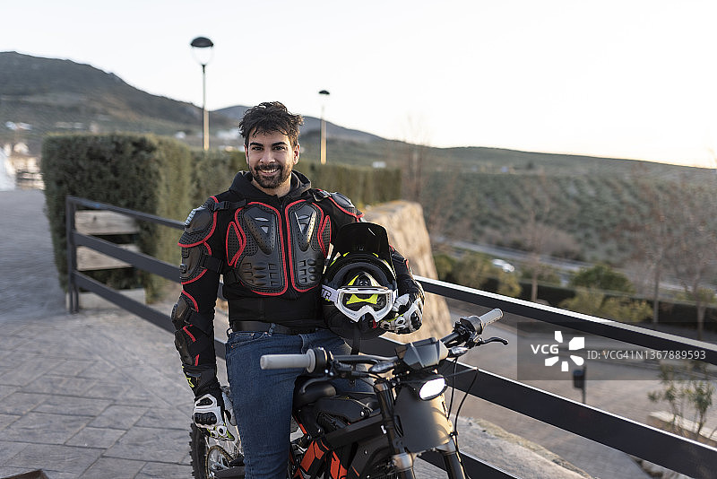 三十多岁男人日落时在观景点与电动摩托车合影图片素材