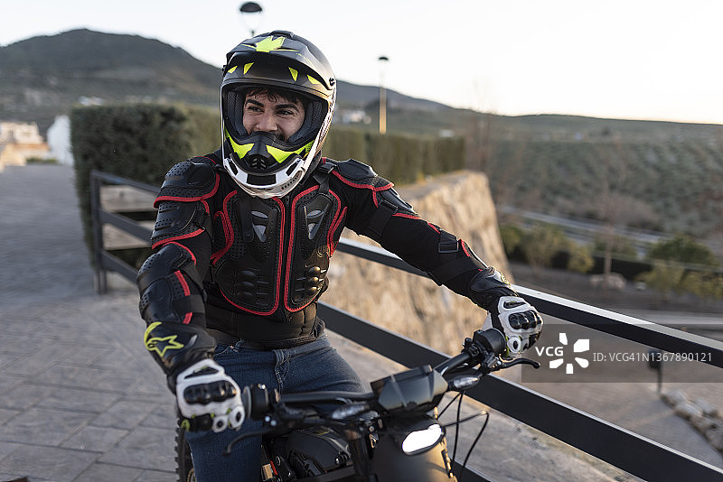 三十多岁男人日落时在观景点与电动摩托车合影图片素材