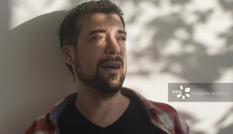 压力大，悲伤哭泣的男人坐在室内图片素材