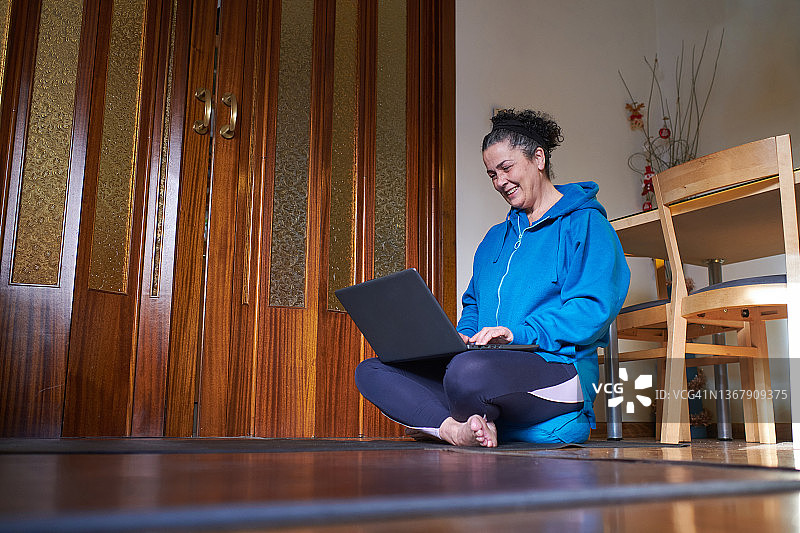 中年妇女在家中用笔记本电脑远程工作（侧视图）图片素材