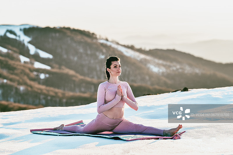 微笑的女瑜伽老师在雪山练习完全劈叉图片素材