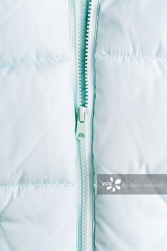 绗缝夹克上的拉链：带拉链的羽绒服纹理特写图片素材
