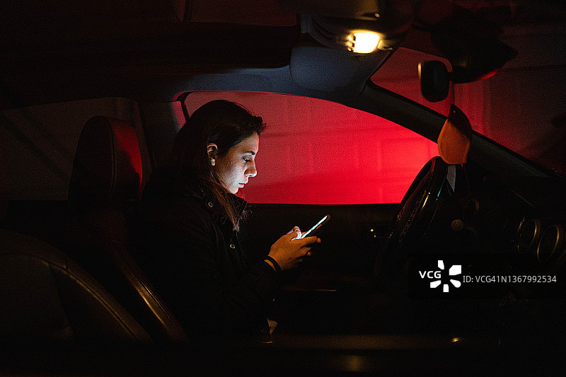 沮丧的青少年女孩在车里用手机发短信图片素材