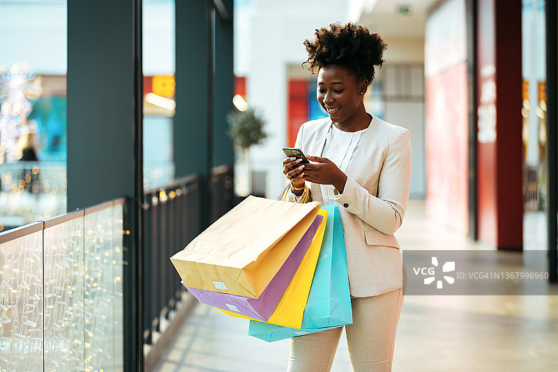 年轻女子购物时使用智能手机的镜头图片素材