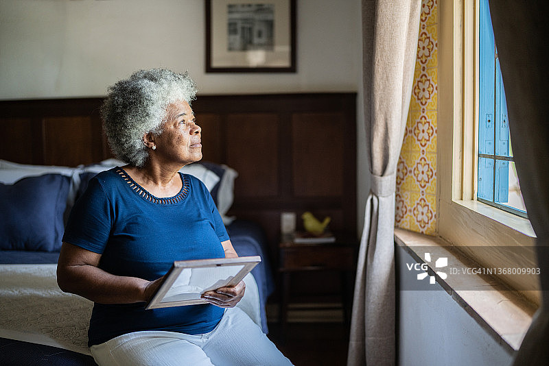 拿着相框思念家人的年长女人图片素材