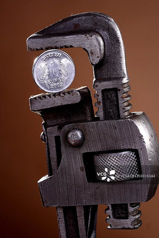 扳手拿着卢比硬币，特写图片素材