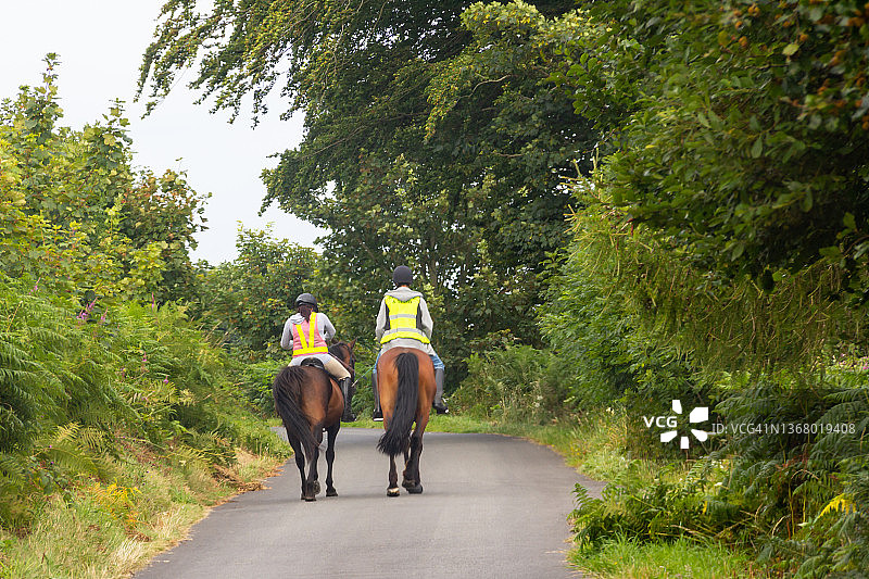 年轻情侣在威尔士乡村小路上骑马图片素材