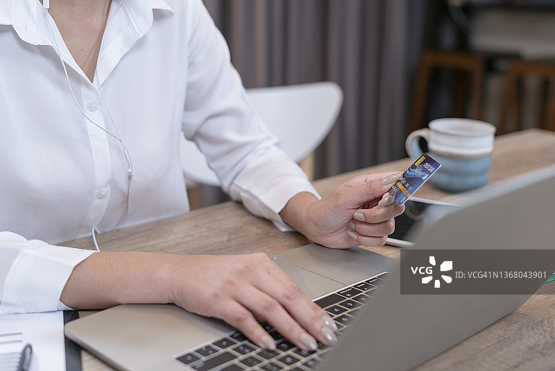 亚洲女性在家用信用卡在网上购物图片素材