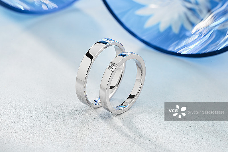 蓝色和白色背景上的一对时尚银色结婚戒指图片素材