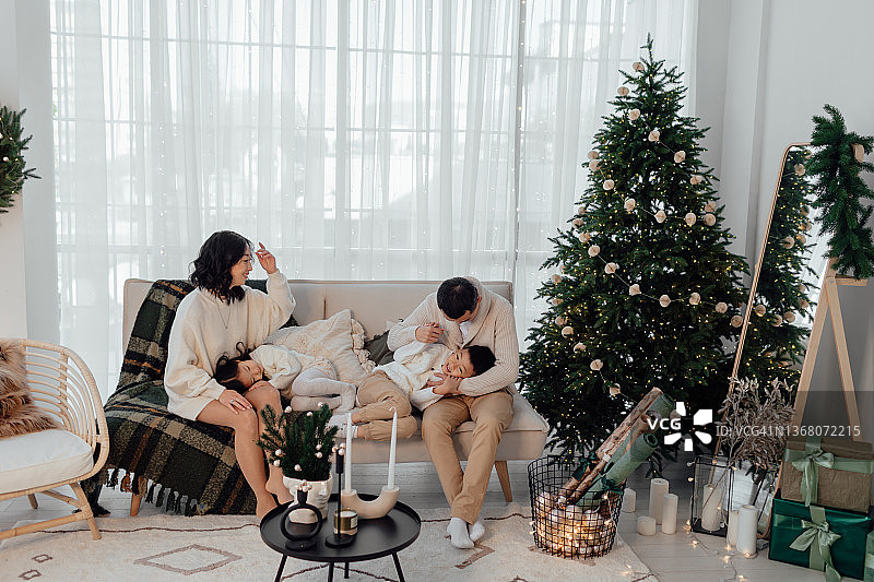 年轻的亚洲家庭在圣诞树旁的沙发上图片素材