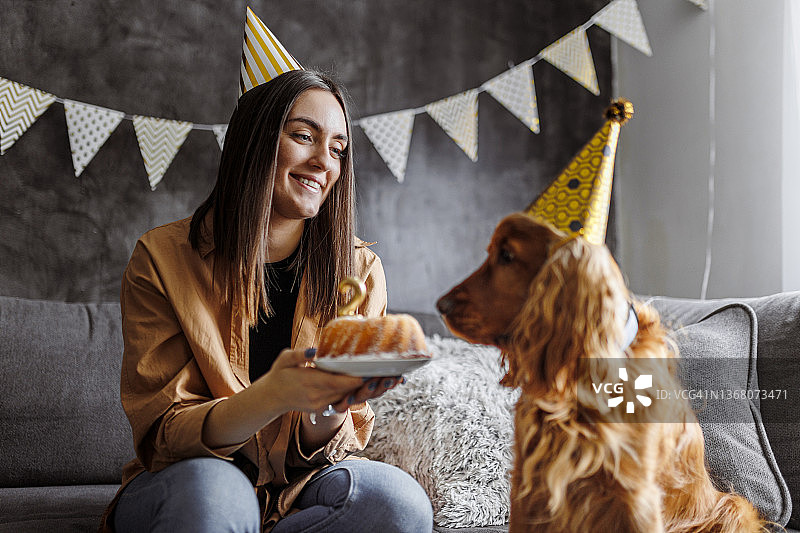 微笑的女人在家和她的狗一起庆祝狗的生日图片素材
