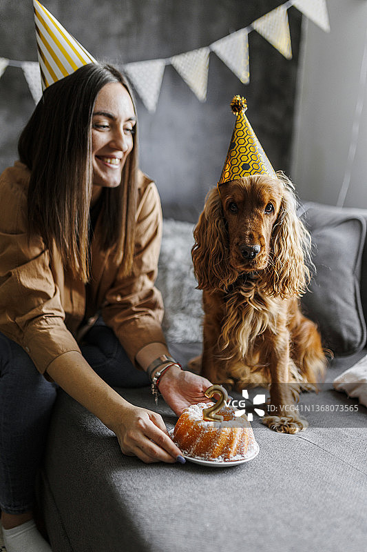 微笑的女人在家和她的狗一起庆祝狗的生日图片素材