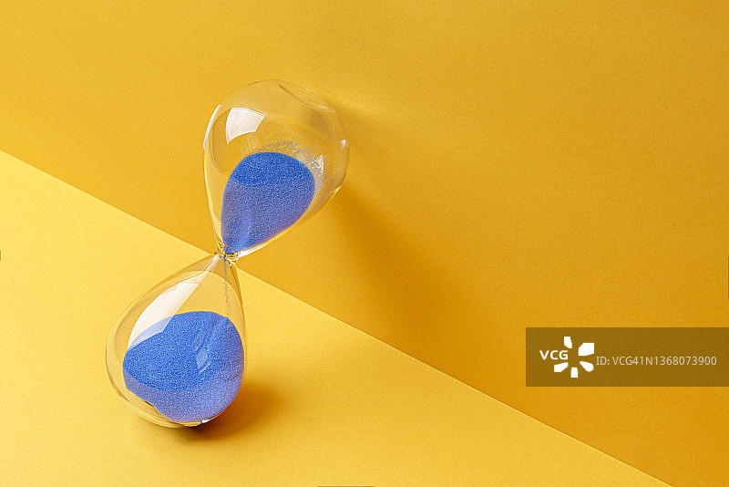 黄色背景上的蓝色沙漏图片素材