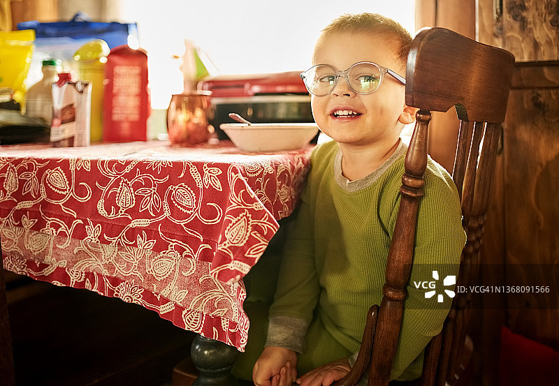 可爱的男孩坐在生态小屋的早餐桌旁图片素材
