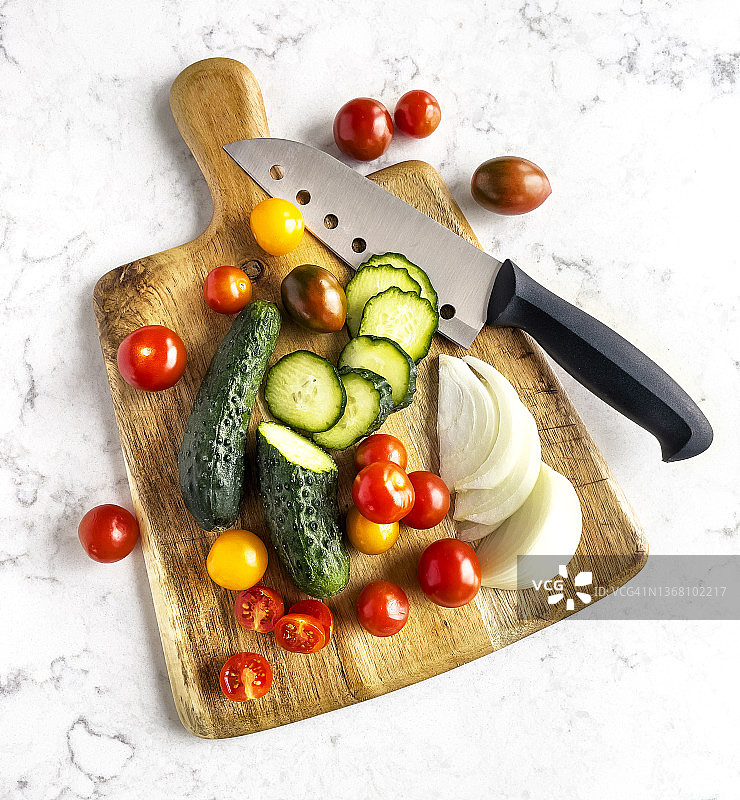 白色大理石背景上砧板上的沙拉食材（番茄、黄瓜和洋葱）图片素材
