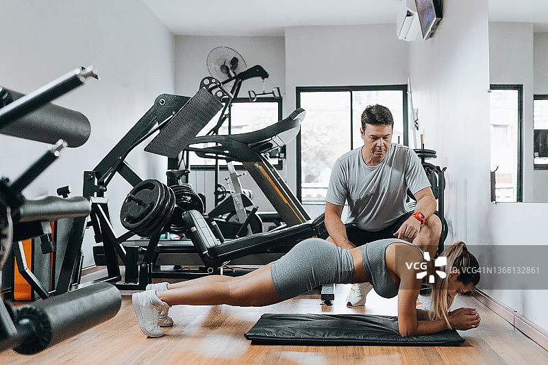 私人教练指导运动员进行腹部平板支撑图片素材