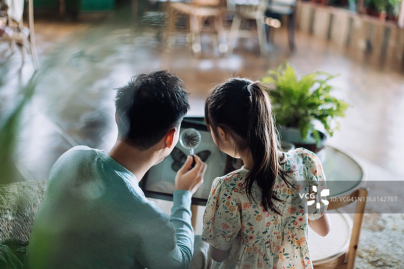 亚洲父女在家用放大镜观察昆虫标本图片素材
