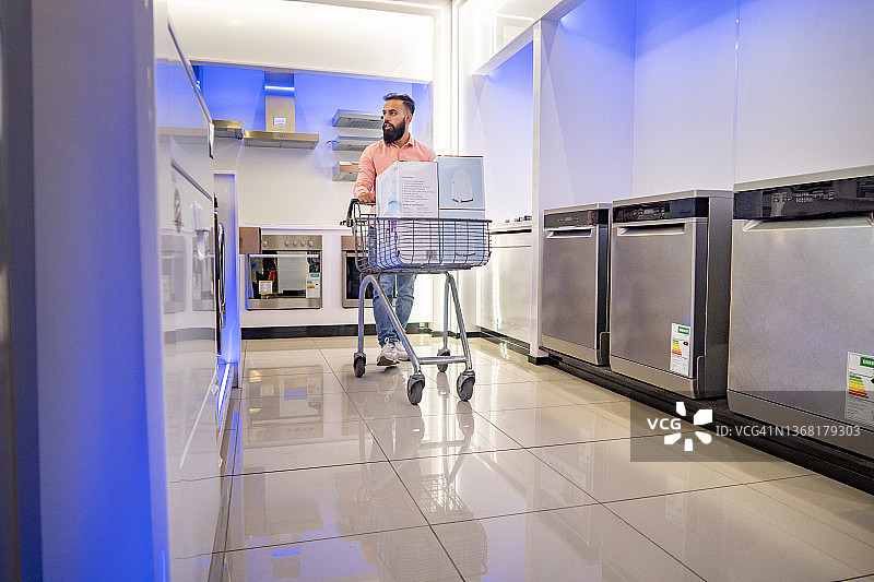 男子在电器商店里推着购物车图片素材