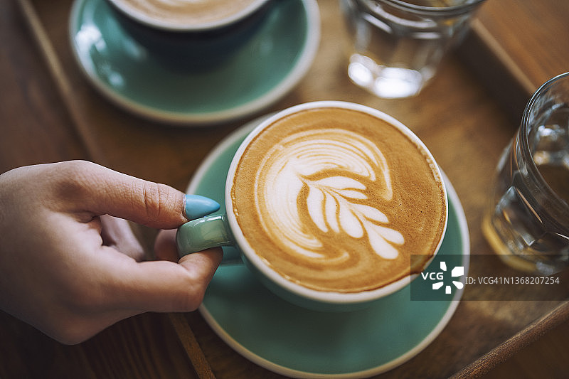 在咖啡馆里拿着咖啡拿铁的女人图片素材