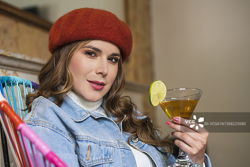 拉丁裔女人坐在小酒吧里，手里拿着一杯酒，被拍照图片素材