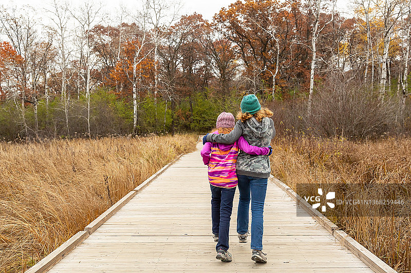 在浮动木板路上互相搂着肩膀的女孩们图片素材