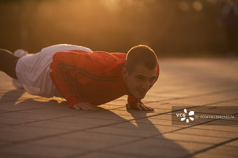 一位年轻人在阳光明媚的春天锻炼，做平板支撑图片素材