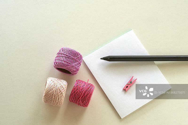 三根粉色棉线和一张带黑色铅笔的纸，顶部视图有复制空间图片素材