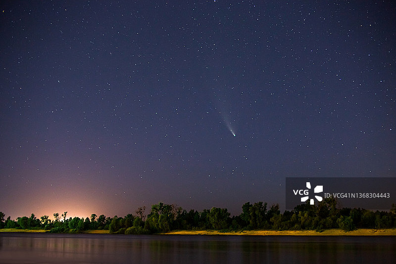夜空中的彗星。夏季星空。天空中的星星。美丽的夜景。长时间曝光。概念摄影。水面上的雾。大气景观。图片素材