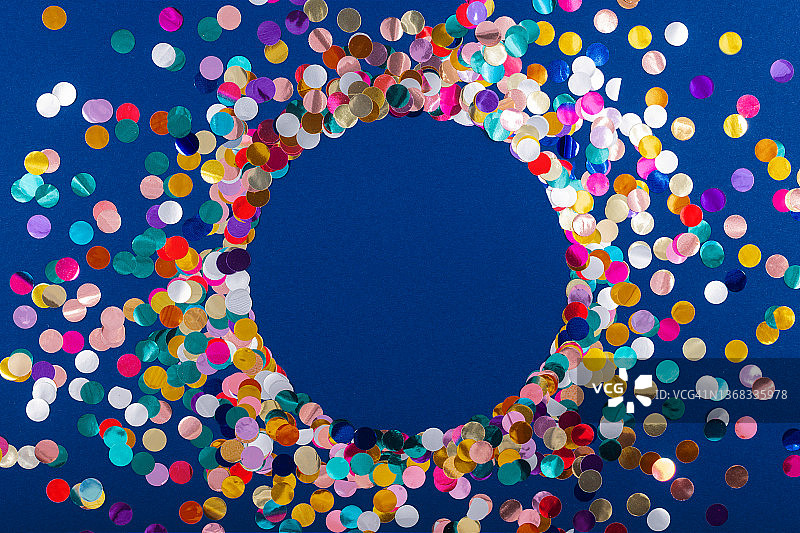 蓝色背景上的圆形五彩纸屑亮片框架与文案空间图片素材