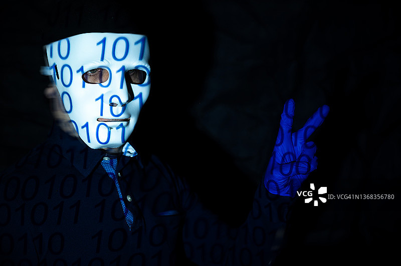 戴着白色面具和二进制代码的人做出胜利手势：成功，代表着人与机器、编程、虚拟世界和未来图片素材