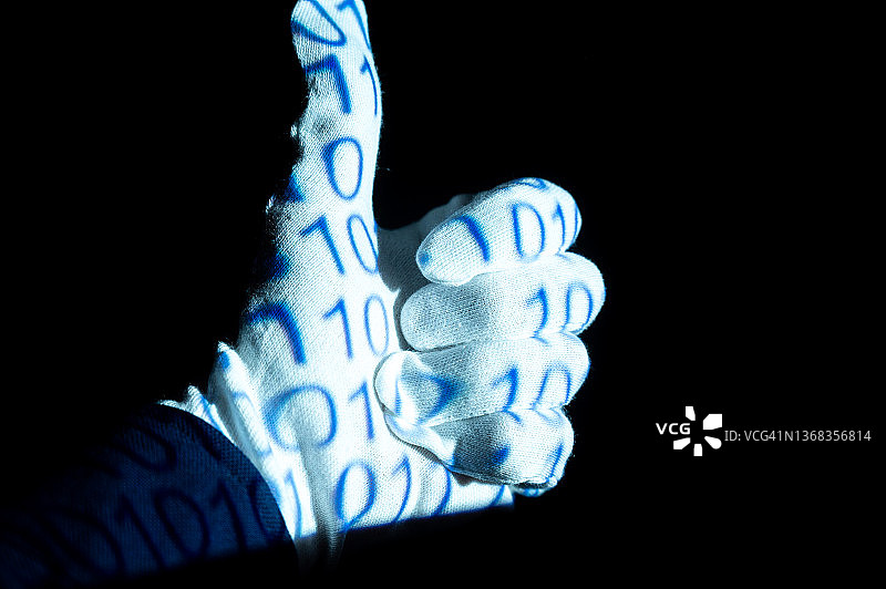 戴白色手套的手，表面有基于0和1的二进制代码：成功。代表人类与机器、编程、虚拟世界和未来。图片素材