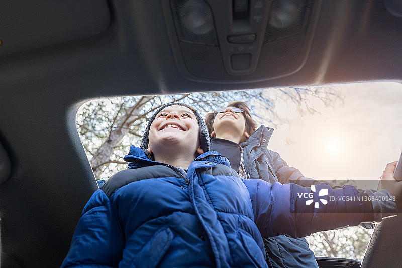 快乐的兄弟在秋天享受汽车天窗上的自由图片素材