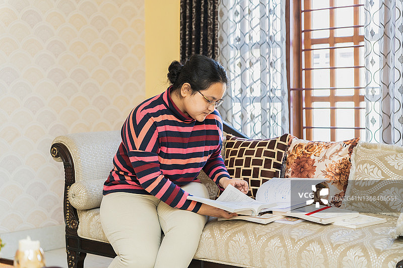 在客厅做作业的年轻亚洲女性图片素材