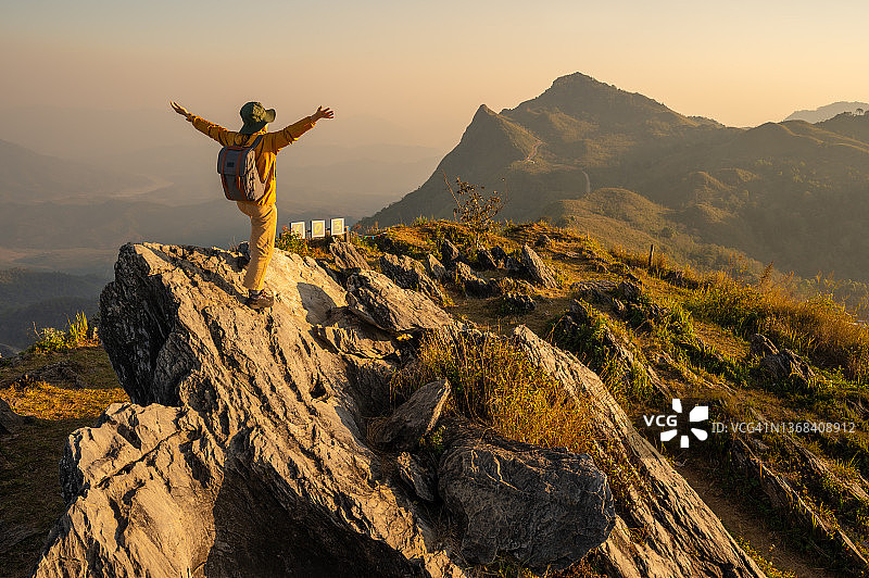 在泰国清莱府帕唐山上“103峰”顶攀登的女游客举起双手图片素材