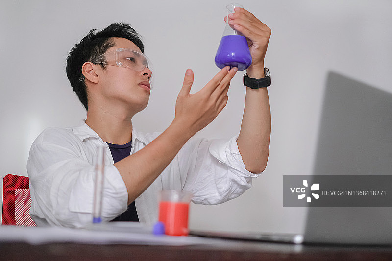 年轻科学家检查锥形瓶中的紫色液体图片素材