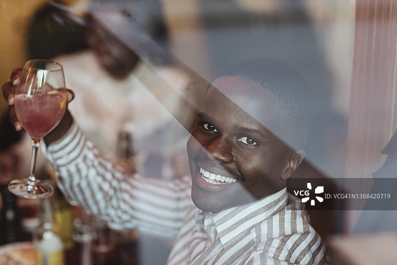 透过餐厅玻璃杯看到的拿着葡萄酒杯的微笑年轻人 портрет图片素材