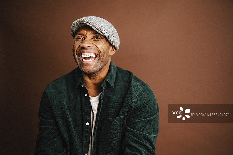 中年男人在演播室里对着棕色背景大笑图片素材