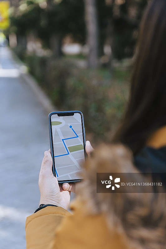 女人使用智能手机上的GPS导航应用程序在城市中导航和寻找方向图片素材