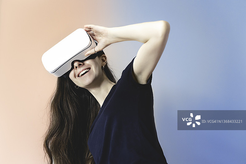 年轻女人正在享受虚拟现实眼镜，快乐地笑着图片素材