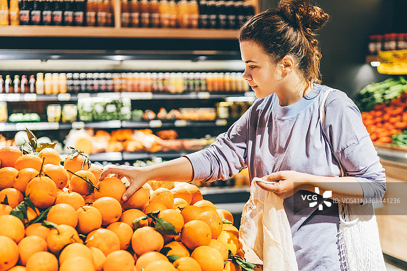 在市场选择橙子并使用可重复使用的环保袋的女人图片素材