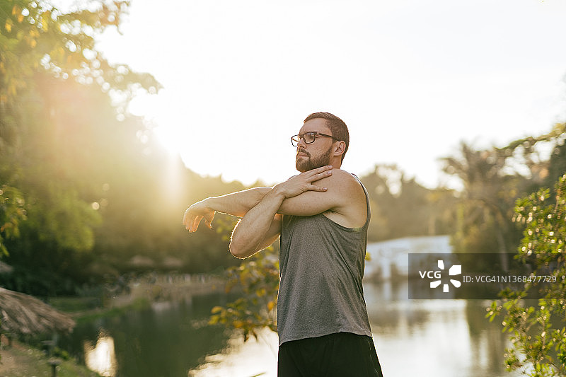 在日落时分的公园里伸展身体的运动员图片素材