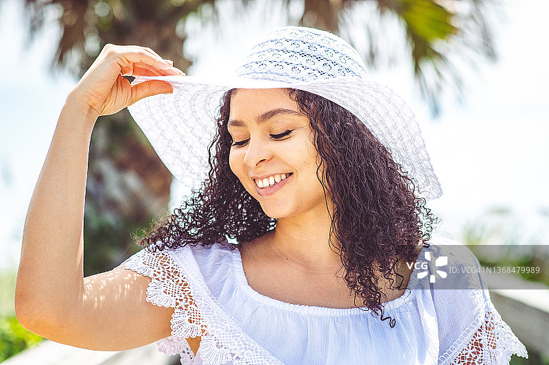 戴着遮阳帽的非裔加勒比女性享受热带海滩假期图片素材