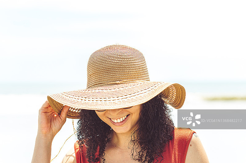 在热带天堂度假时戴着草帽的快乐无忧的非洲-加勒比女人肖像图片素材