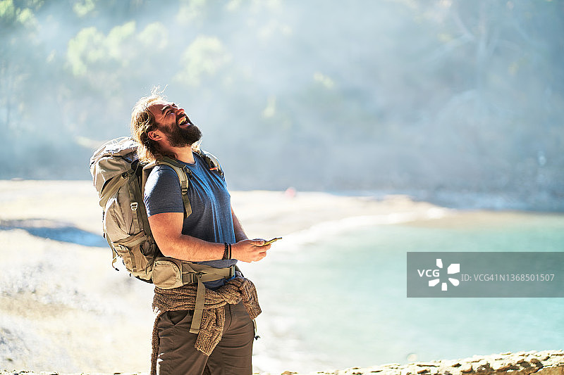 在海边用智能手机的快乐男人图片素材