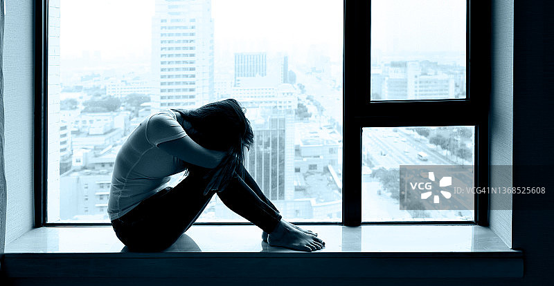 悲伤的女人坐在窗台上图片素材