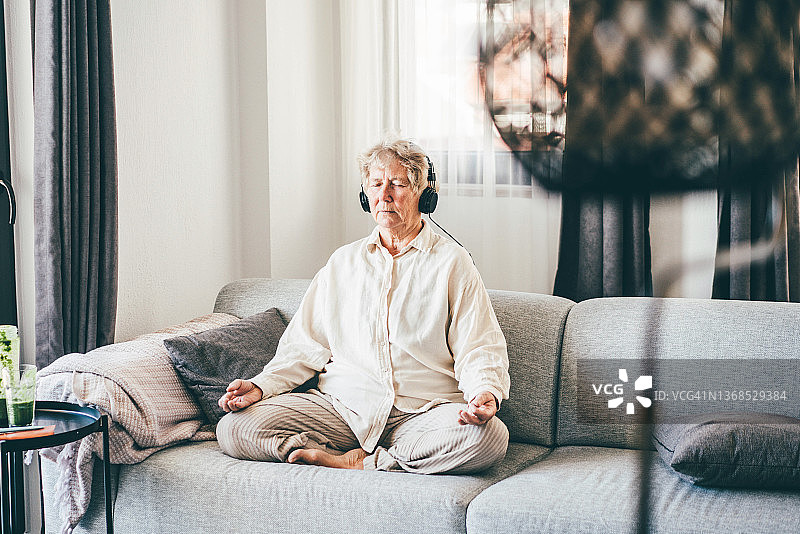 年长的白人妇女在家练习瑜伽和冥想音乐图片素材