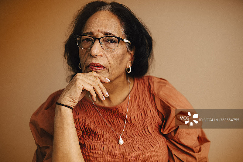年长妇女的肖像，手放在下巴在工作室图片素材